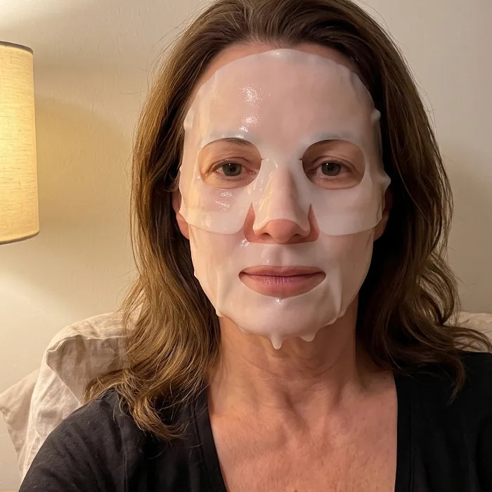 Mujer en la cama, por la noche, con la mascarilla de hidrogel recién puesta, blanca